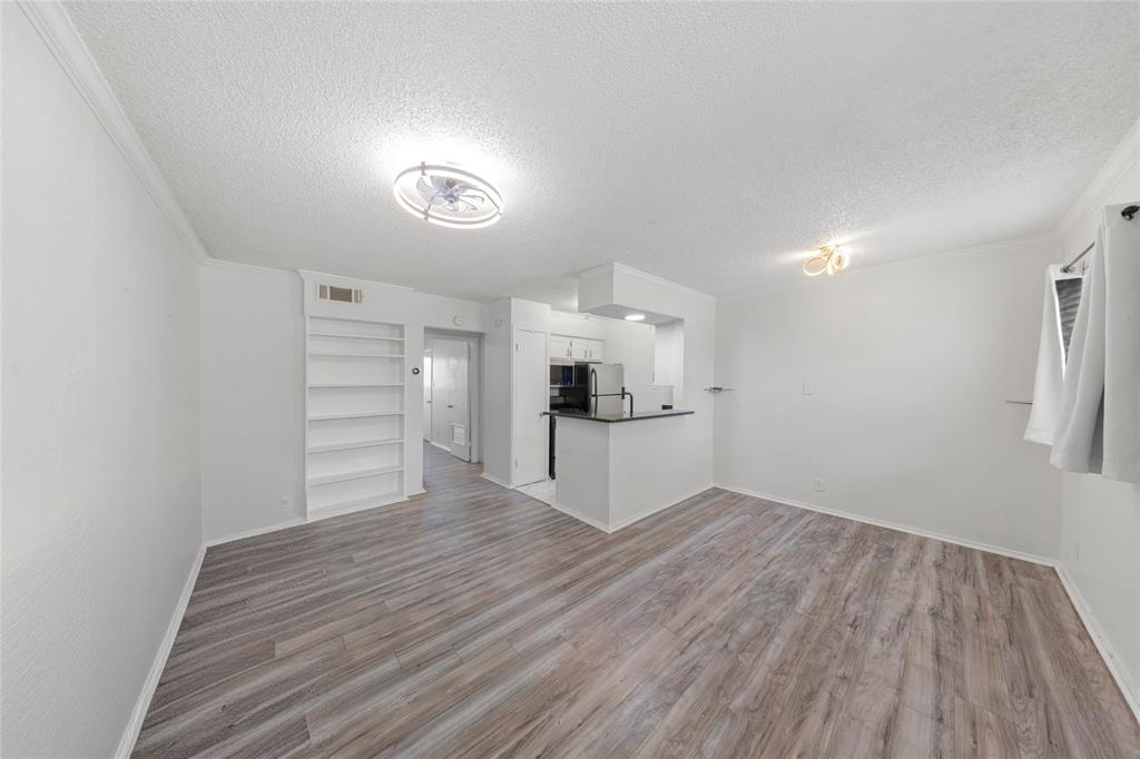 2401 Manor Road, Unit 123 Austin, TX 78722 - Photo 3 of 22 A streamlined open-concept living area with plank flooring transitions seamlessly into a compact, efficient kitchen space.