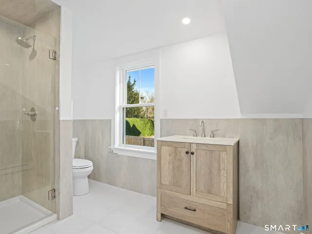 a bathroom with a granite countertop sink a toilet and shower