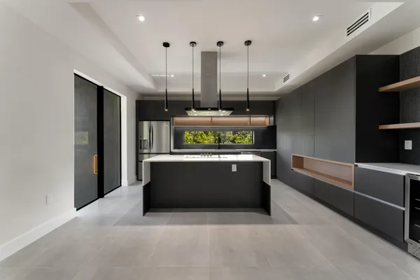 a large kitchen with stainless steel appliances a large counter top a stove and a wooden floors