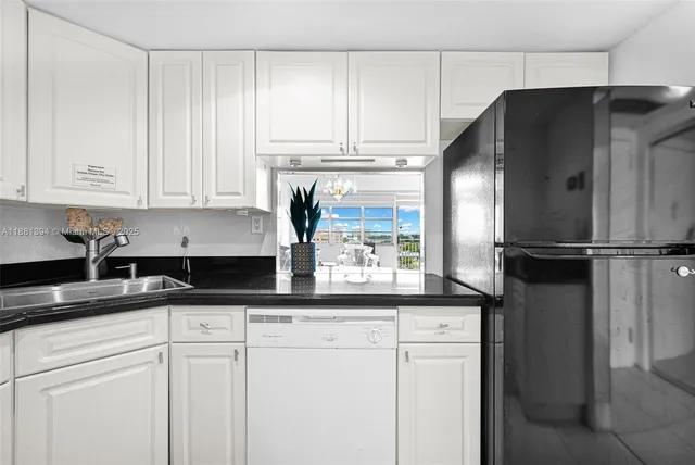 a kitchen with granite countertop white cabinets and stainless steel appliances