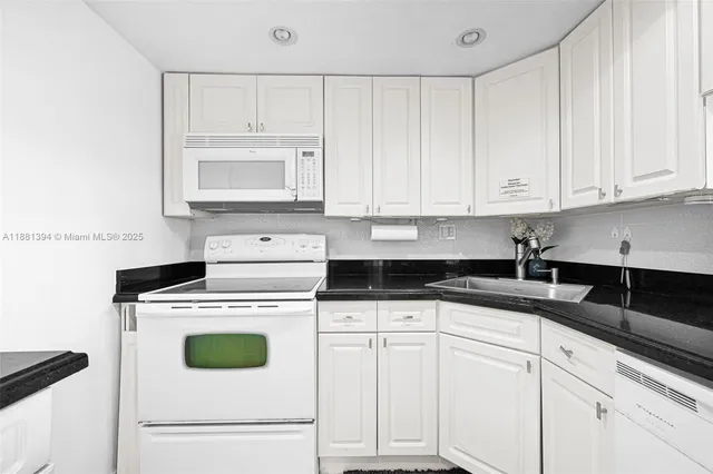 a kitchen with granite countertop white cabinets and white appliances