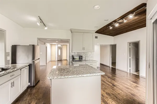 a kitchen with granite countertop kitchen island a sink stainless steel appliances and cabinets