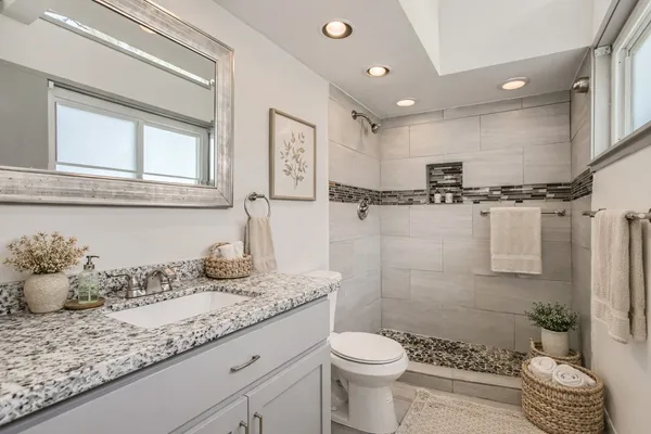 a bathroom with a granite countertop sink mirror vanity and toilet
