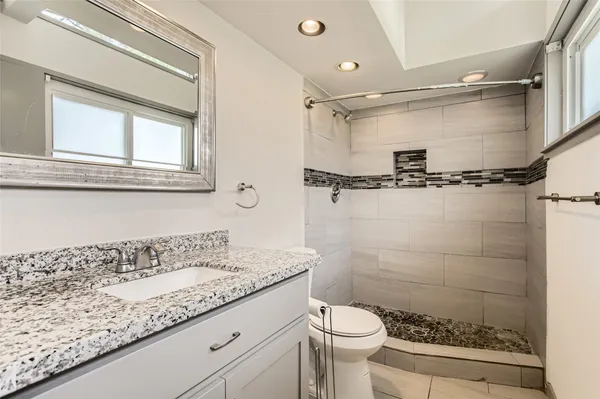 a bathroom with a granite countertop sink a toilet and shower