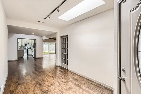 a view of a hallway with wooden floor and a living room