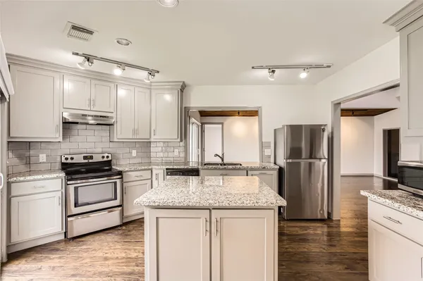 a kitchen with kitchen island granite countertop a stove and a refrigerator