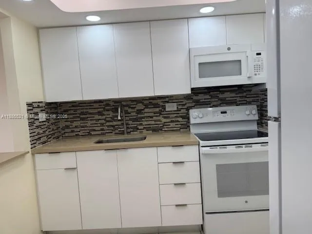a kitchen with granite countertop white cabinets and white appliances