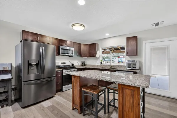 a kitchen with stainless steel appliances granite countertop a refrigerator a stove top oven a sink and dishwasher