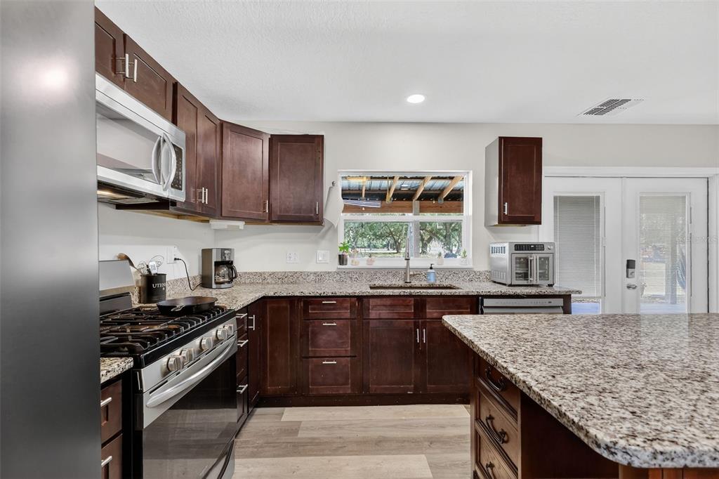 4533 Southwest 37th Terrace Bushnell, FL 33513 - Photo 18 of 58 a kitchen with stainless steel appliances granite countertop a stove a sink and a microwave