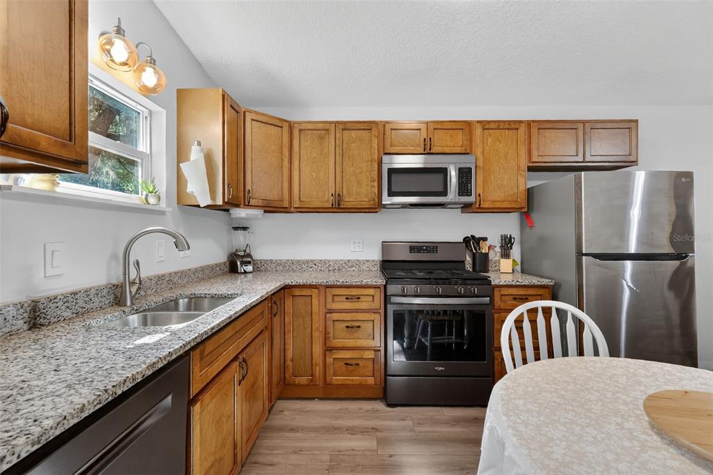 4533 Southwest 37th Terrace Bushnell, FL 33513 - Photo 37 of 58 a kitchen with stainless steel appliances granite countertop a refrigerator a stove top oven a sink and dishwasher