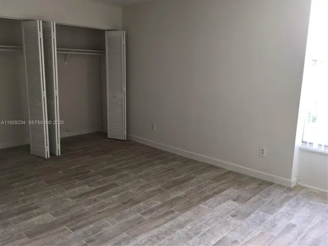 an empty room with wooden floor and closet