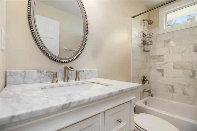 a bathroom with a granite countertop bathtub a sink and a mirror
