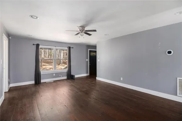 a view of an empty room with wooden floor and a window