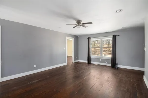 a view of an empty room with wooden floor and a window