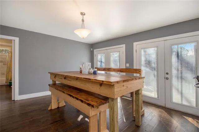 a room with stainless steel appliances kitchen island granite countertop a stove a refrigerator a sink a dining table and chairs with wooden floor