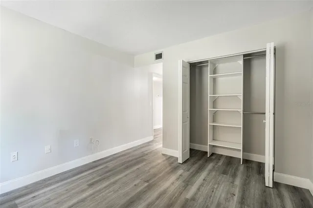 a view of an empty room with wooden floor and closet