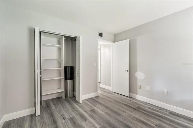 a view of an empty room with closet and a window