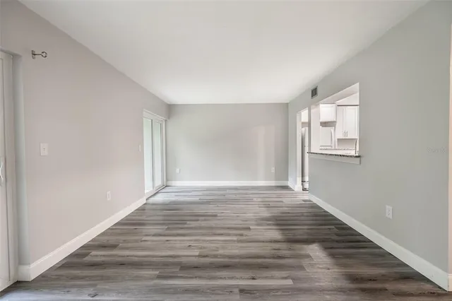 a view of an empty room with wooden floor and window