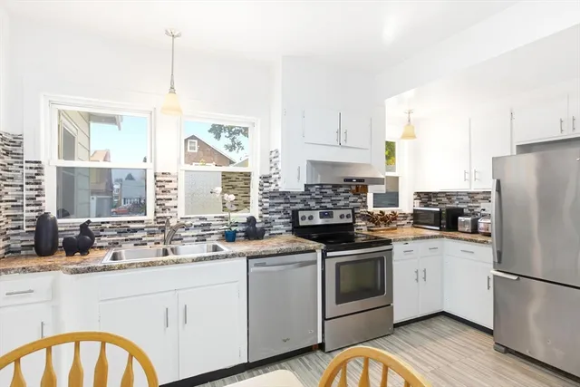 a kitchen with white cabinets appliances and a window