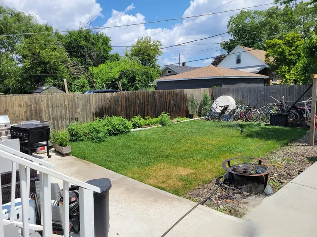 a view of a backyard with plants and brick wall