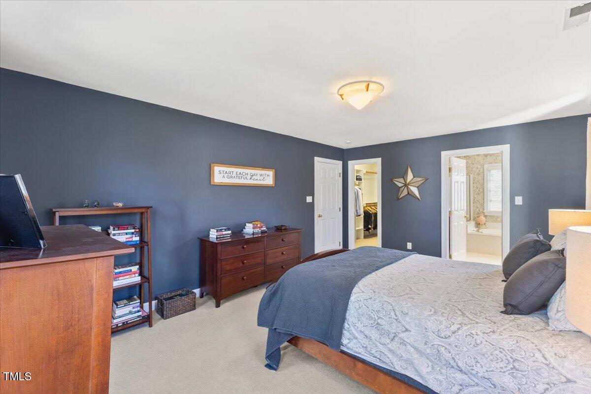 4617 Wee Burn Trail Raleigh, NC 27612 - Photo 35 of 70 a bedroom with a bed and a chandelier