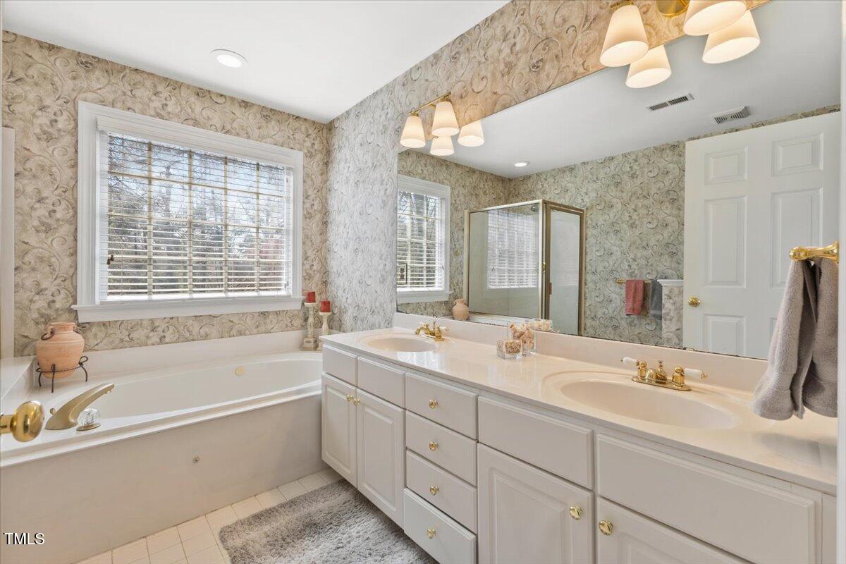 4617 Wee Burn Trail Raleigh, NC 27612 - Photo 37 of 70 a bathroom with a tub a sink double vanity and a mirror