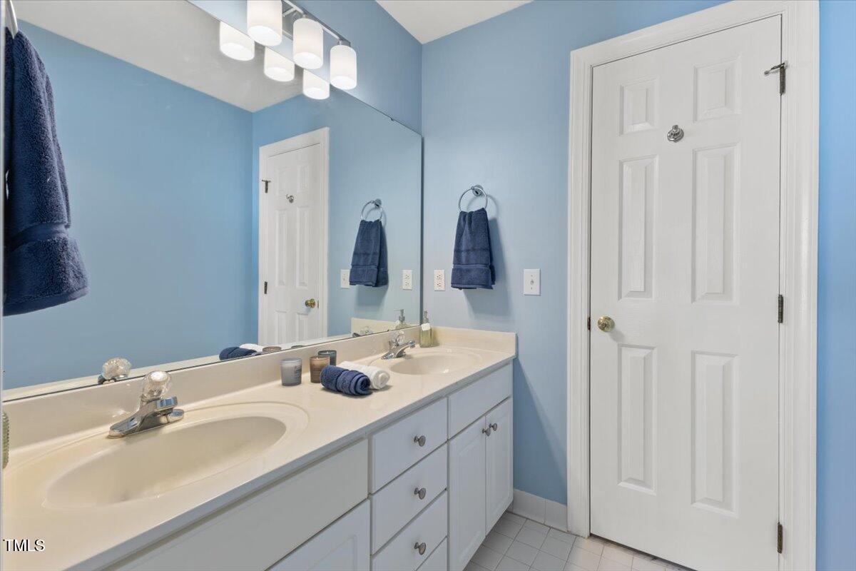 4617 Wee Burn Trail Raleigh, NC 27612 - Photo 52 of 70 a bathroom with double vanity sinks a vanity a lamp and a mirror
