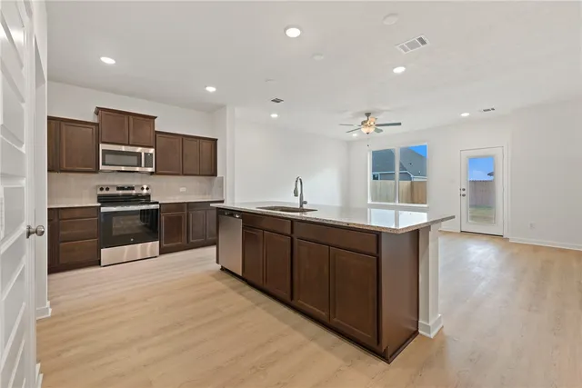 a kitchen with stainless steel appliances kitchen island granite countertop a stove a sink and a refrigerator