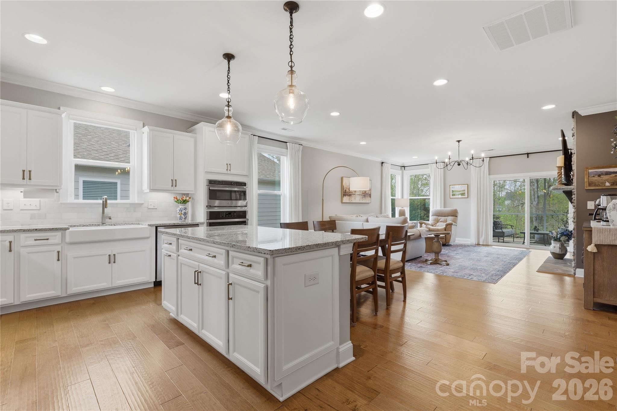 3023 Eagle Ridge Lane Indian Trail, NC 28079 - Photo 10 of 47 a open kitchen with granite countertop a stove top oven a sink a dining table and chairs with wooden floor