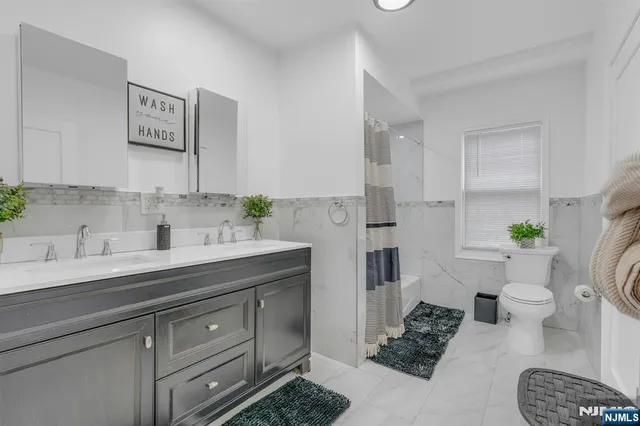 a spacious bathroom with a granite countertop sink a toilet a mirror and shower