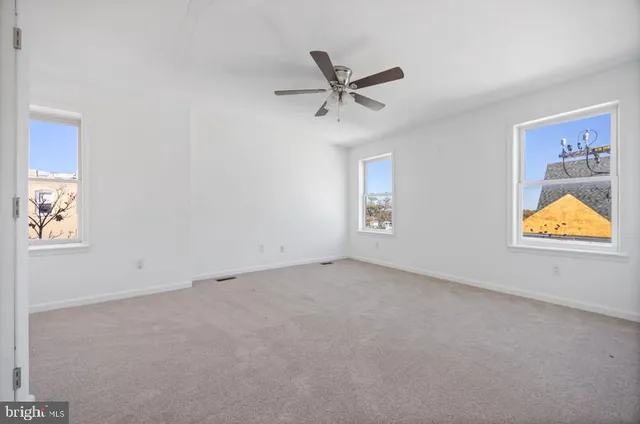 an empty room with a ceiling fan and window
