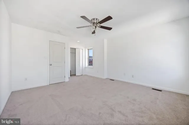 an empty room with chandelier fan and windows