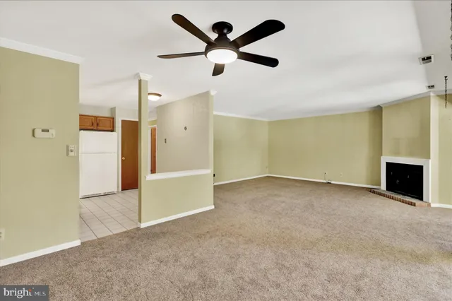 an empty room with fireplace and a ceiling fan