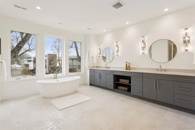 a spacious bathroom with a double vanity sink a large mirror and a bathtub
