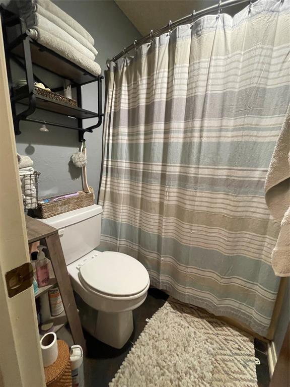814 Plum Street Graham, TX 76450 - Photo 23 of 25 a bathroom with a toilet and a shower curtain
