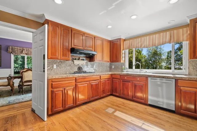 a kitchen with granite countertop wooden cabinets a sink and dishwasher