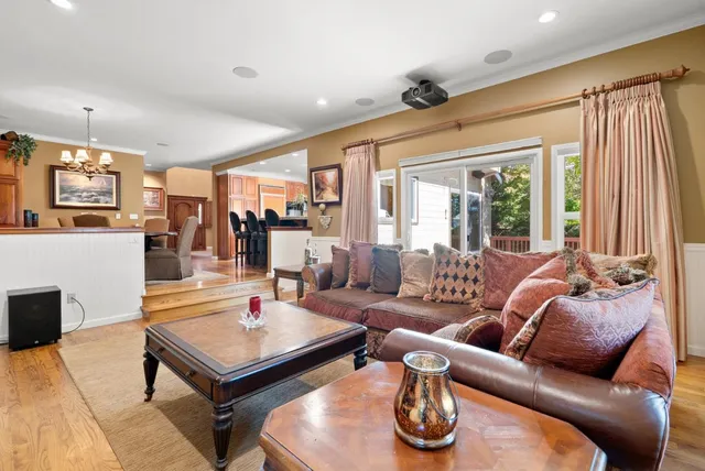 a view of a dining room with furniture a chandelier and large windows