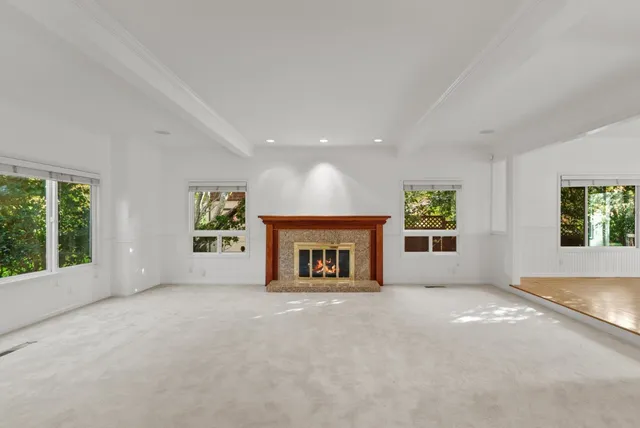 an empty room with windows and fireplace