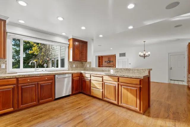 a kitchen with stainless steel appliances granite countertop wooden cabinets a sink and a stove