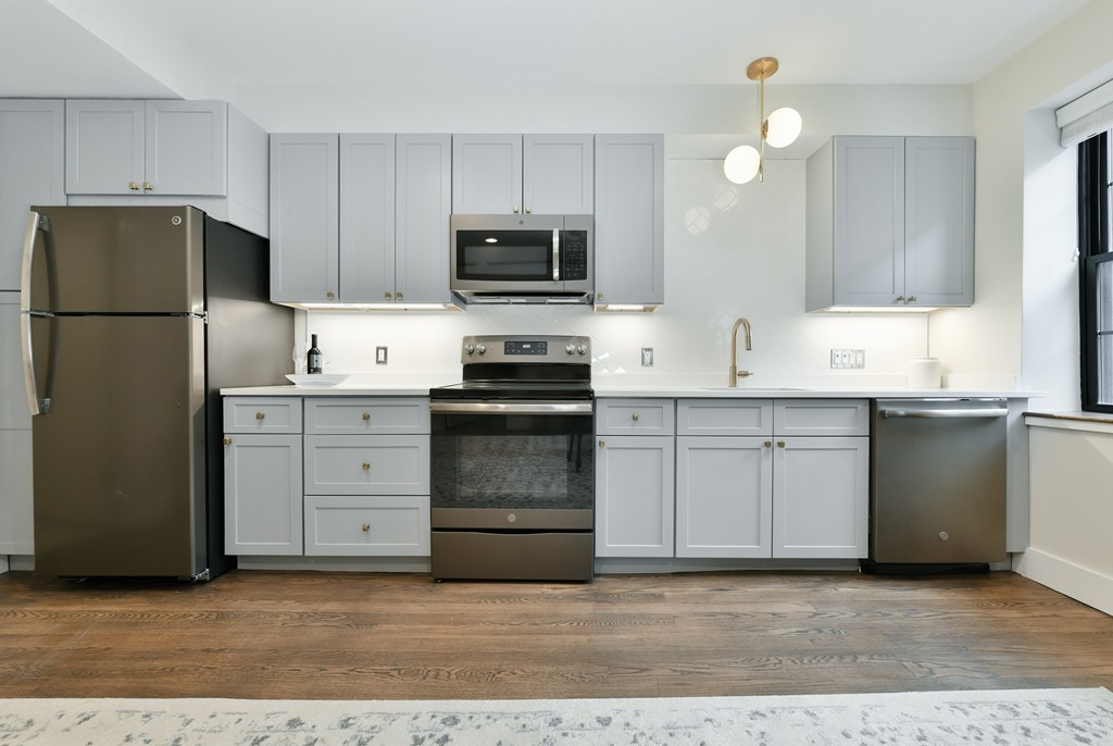 40 Fleet Street, Unit 5 Boston, MA 02113 - Photo 2 of 8 a kitchen with granite countertop a sink stainless steel appliances and white cabinets