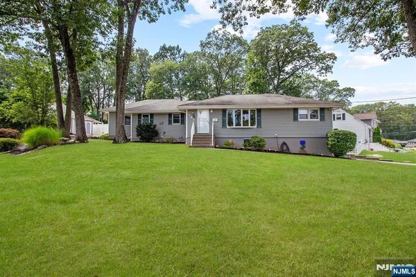a view of a house with a big yard and large trees