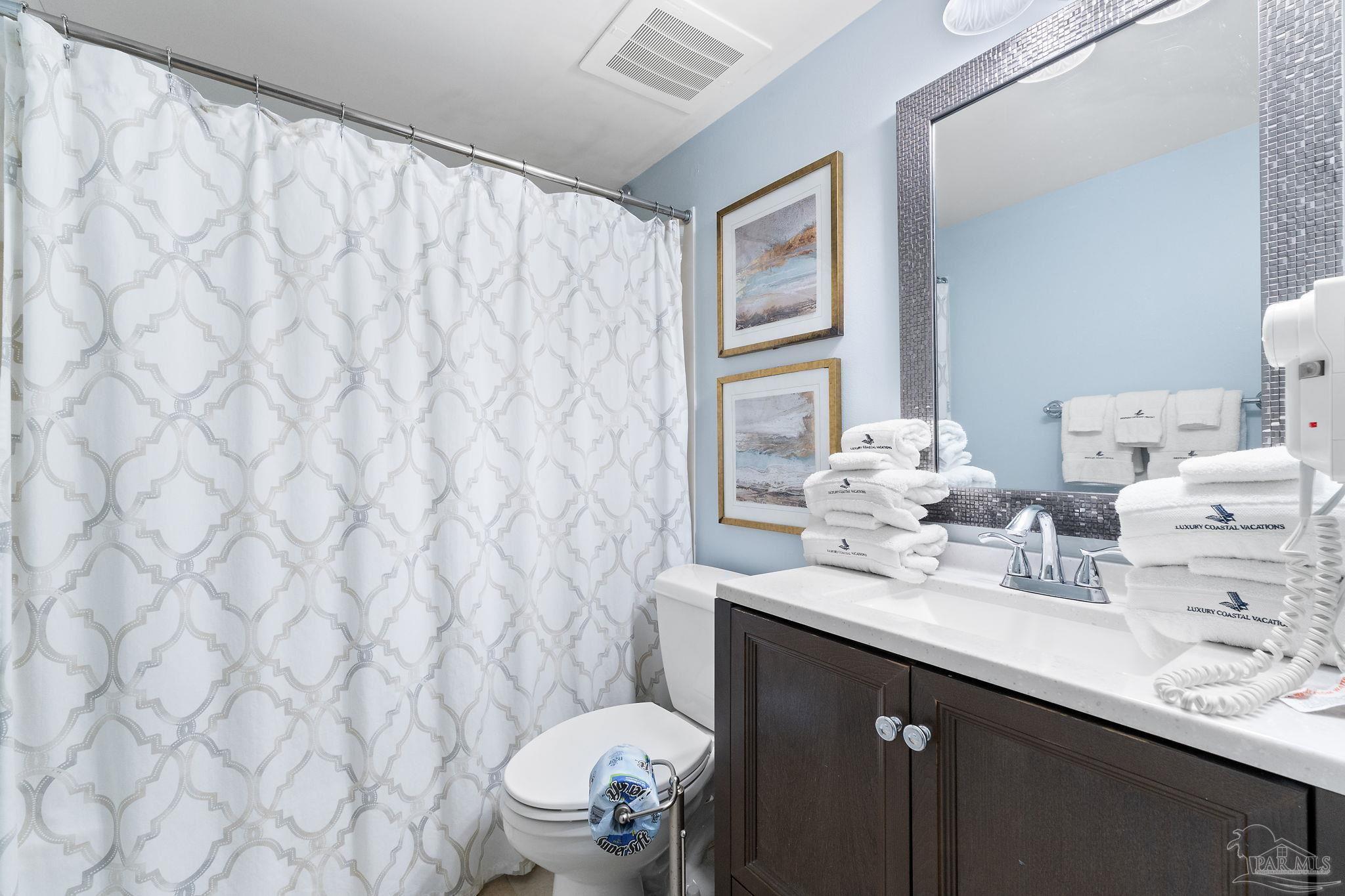 13575 Sandy Key Drive, Unit 335 Pensacola, FL 32507 - Photo 21 of 25 a bathroom with a sink mirror vanity and toilet