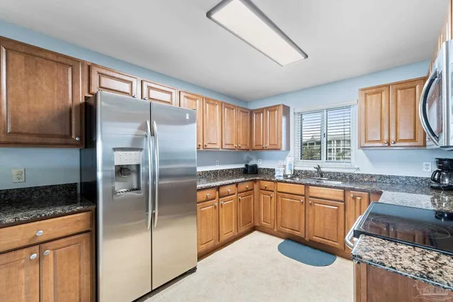 a kitchen with stainless steel appliances granite countertop a refrigerator a sink dishwasher a stove a washer and dryer with wooden floor