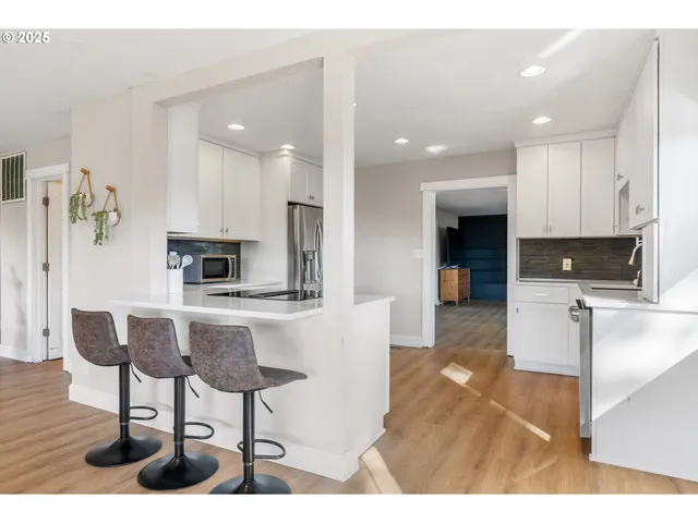 a kitchen with cabinets stainless steel appliances and wooden floor