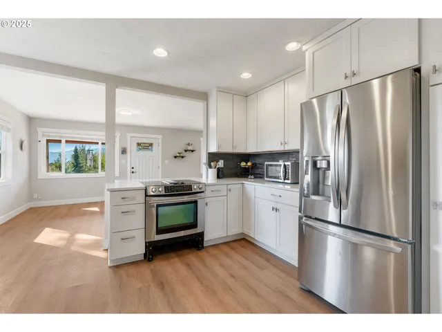 a kitchen with stainless steel appliances granite countertop a stove a sink and white cabinets