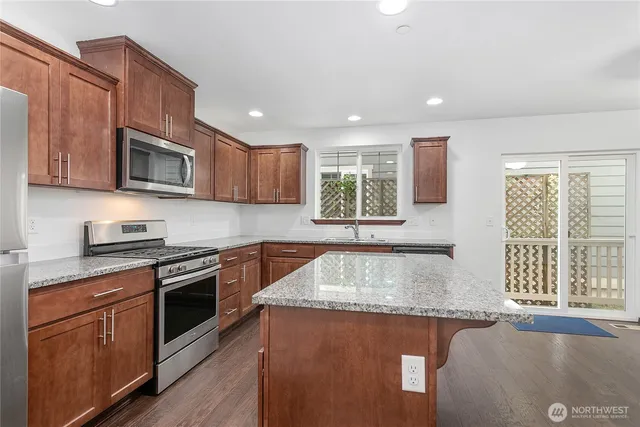 a kitchen with stainless steel appliances granite countertop wooden cabinets a stove a sink and a window