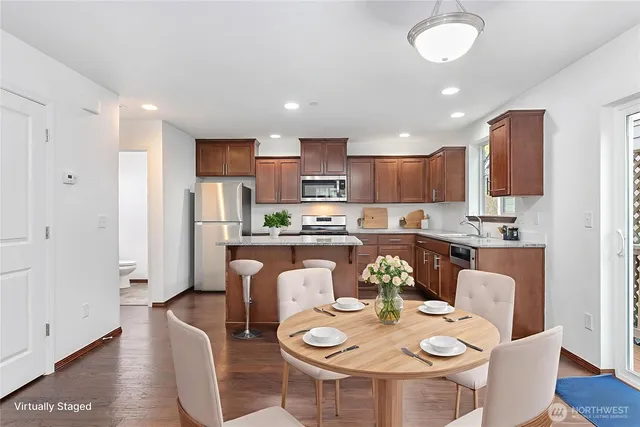 a kitchen with stainless steel appliances granite countertop a stove a refrigerator a kitchen island a dining table and chairs