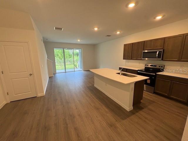 32547 Welling Blade Loop Wesley Chapel, FL 33545 - Photo 3 of 21 a kitchen with stainless steel appliances a white stove top oven a sink dishwasher and wooden floor