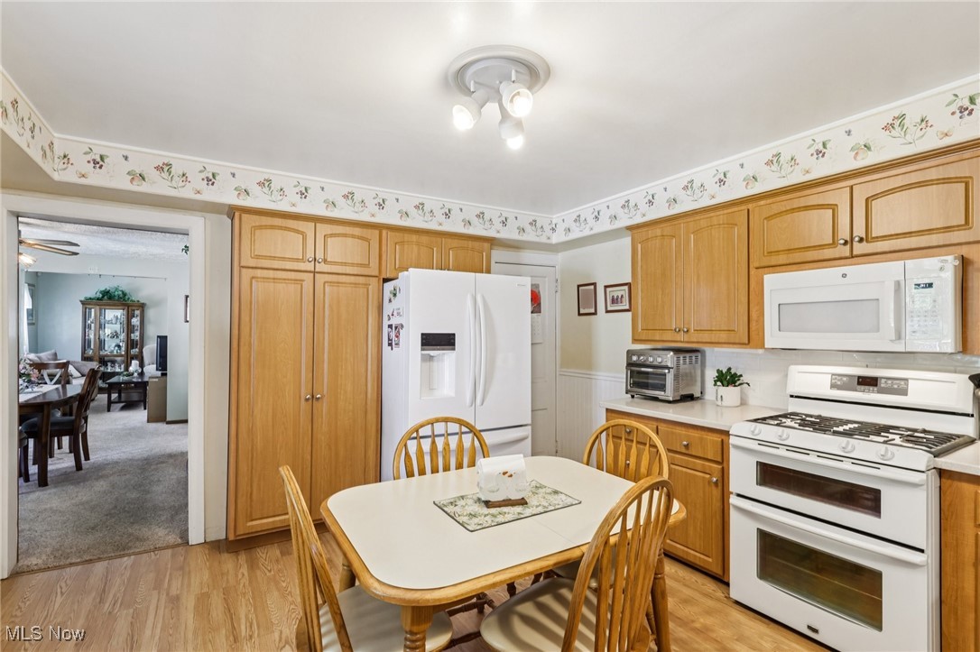 10818 Dixon Road Cleveland, OH 44111 - Photo 16 of 44 Kitchen with white appliances, light wood-type flooring, a wainscoted wall, and light countertops