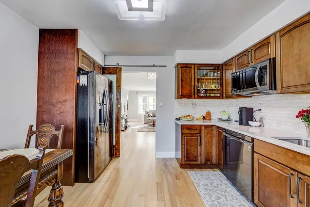 a kitchen with stainless steel appliances granite countertop a refrigerator a stove top oven a sink dishwasher and wooden cabinets with wooden floor